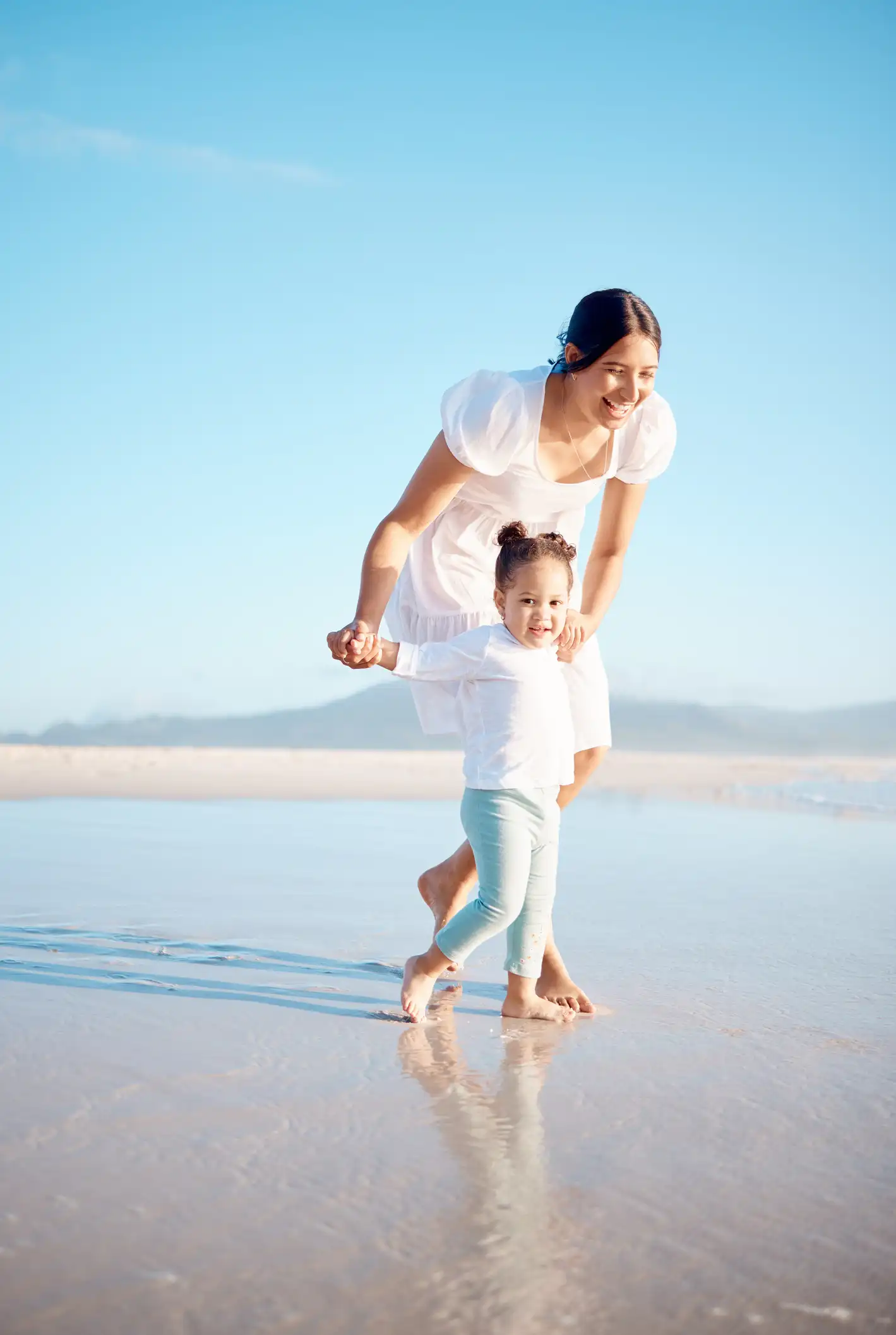 Shot of a young woman at the beach with her adorable daughter